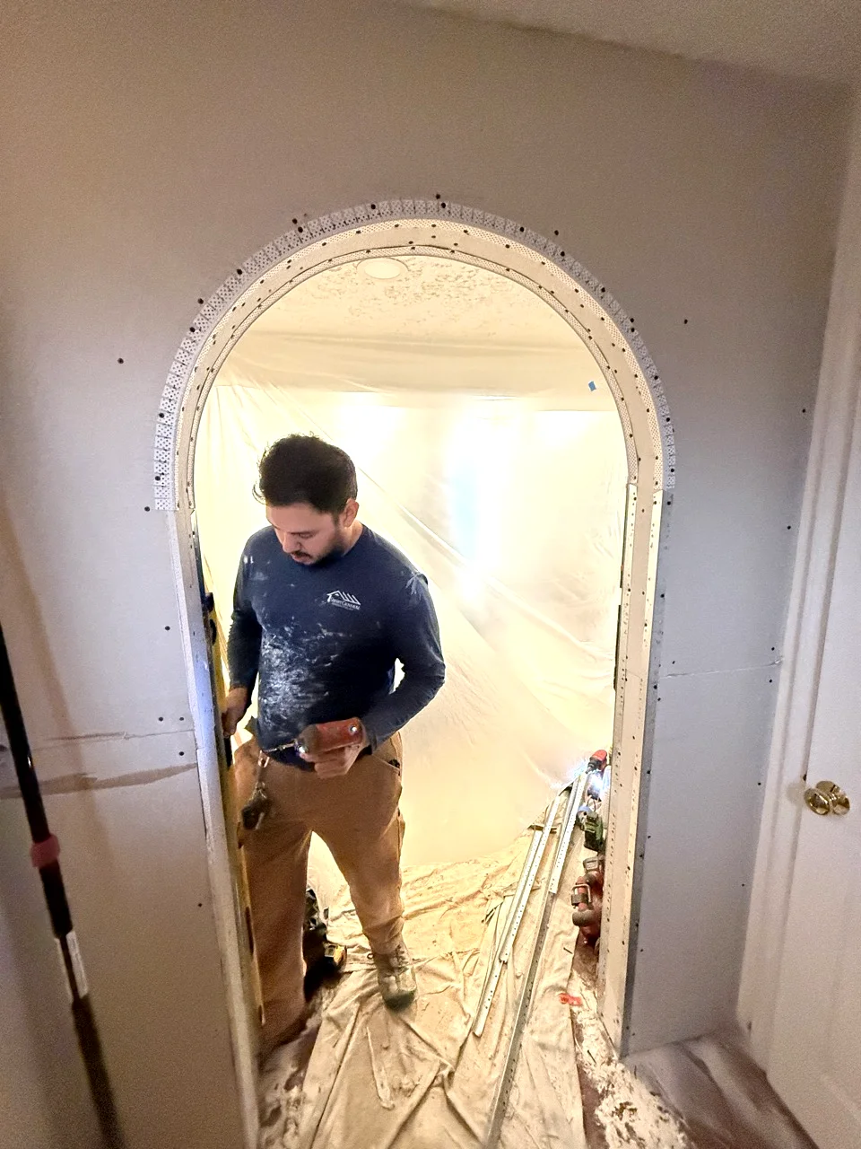 Contractor installing corner bead on arched drywall opening